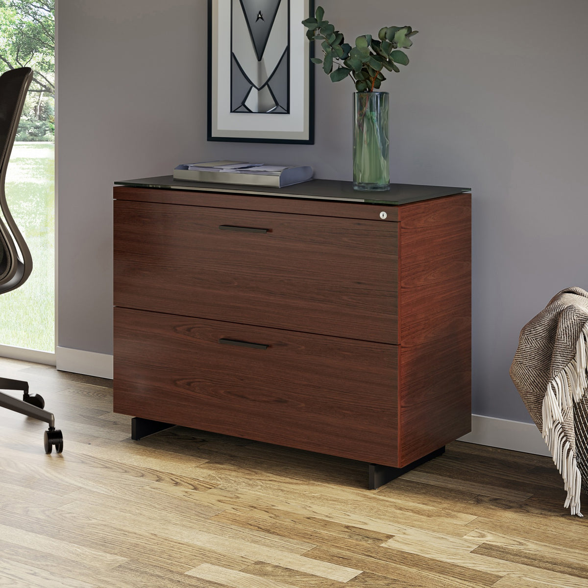 BDi Sequel 20 6116 Lateral File Cabinet in Chocolate Stained Walnut, with a black base, beside a desk, in a home office