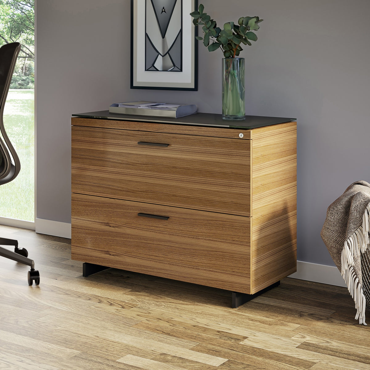 BDi Sequel 20 6116 Lateral File Cabinet in Natural Walnut, with a black base, beside a desk, in a home office