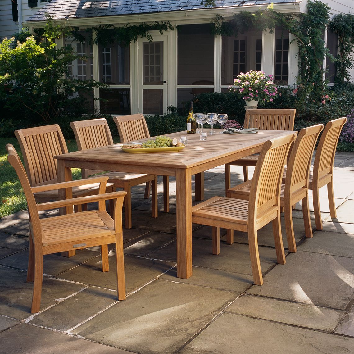 Wooden outdoor dining set with table and chairs on a stone patio