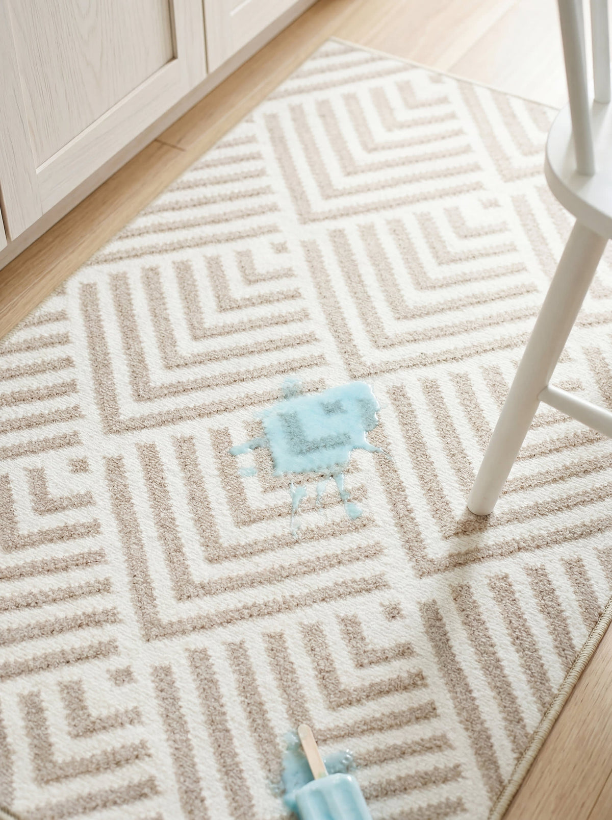 Dash & Albert Cleo Machine Washable Rug in Wilderness Cement, close-up with a stool