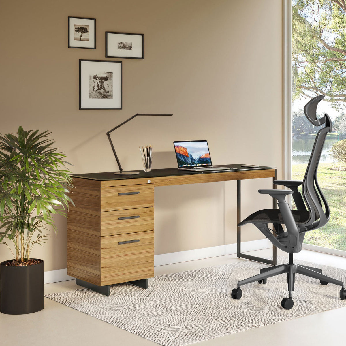 BDi Sequel 20 6112 Desk Extension in Natural Walnut, with a black frame, on a 3-drawer file cabinet beside a multi-function cabinet