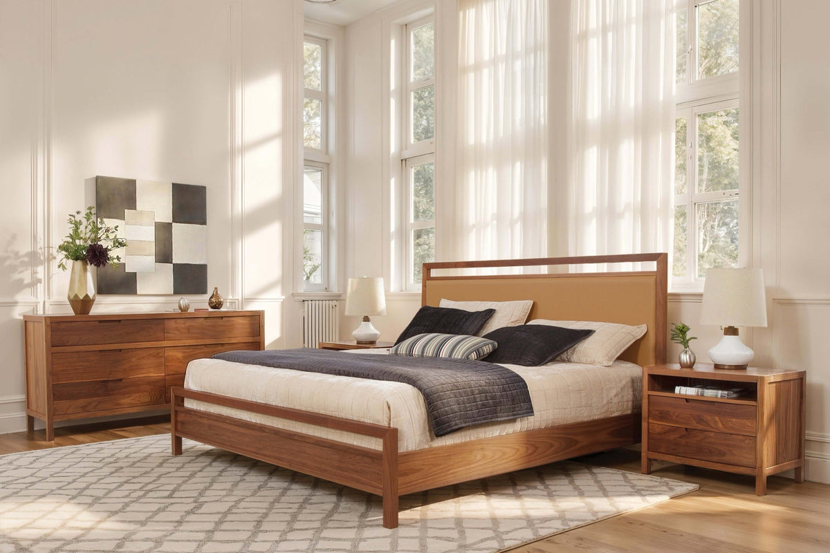 Walnut bed with a caramel upholstered headboard, matching dresser and nightstand in a bright bedroom