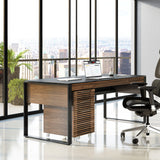 BDi Corridor 6507 Mobile File Cabinet in Natural Walnut, under a desk in a city office