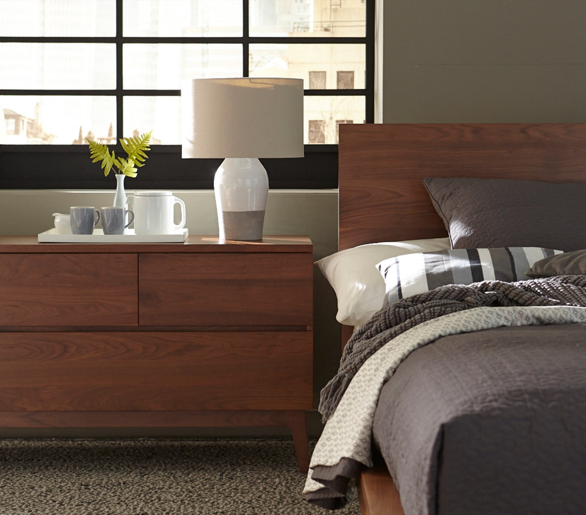 West Bros Serra 4 Drawer Dresser in 80 Walnut, beside the bed in a room setting