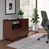BDi Sequel 20 6117 Multi Function Cabinet in Chocolate Stained Walnut, with a black base, beside a compact desk, in a home office