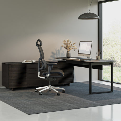 BDi Corridor 6531 L-Shaped Office Desk in Charcoal Stained Ash, in an office beside an open staircase