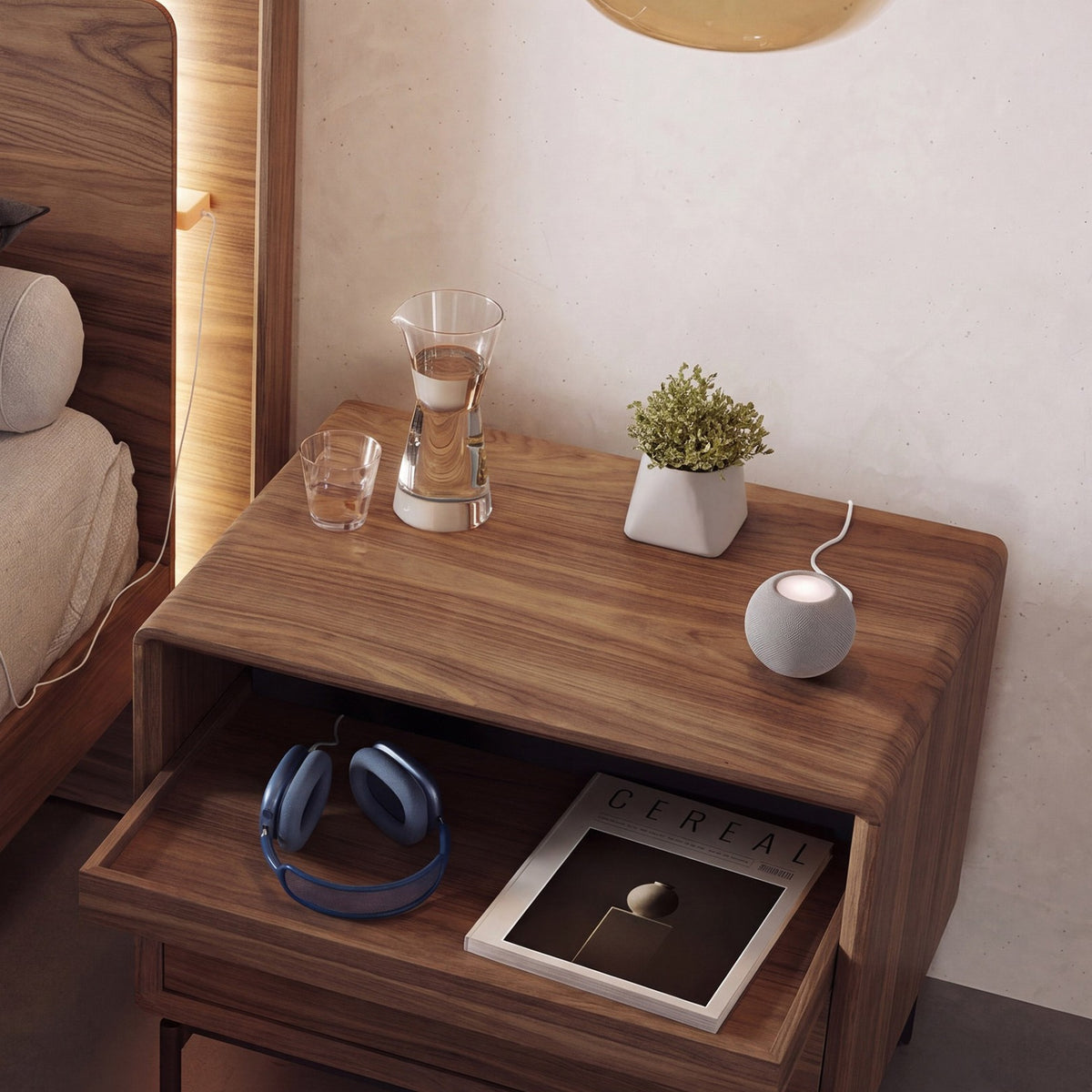 BDi Linq Nightstand in Natural Walnut, 28-inch with the tray pulled out, beside a bed