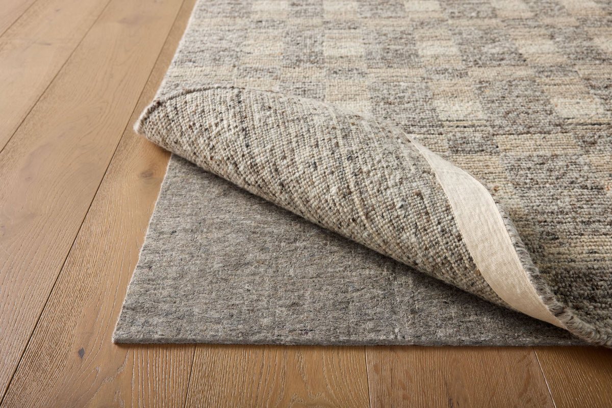 Loloi Loloi- Grip 3/8" Rug Pad in Beige, under a rug on a wood floor