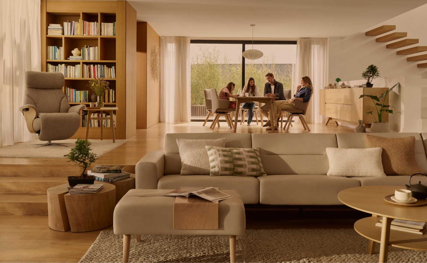 Modern living room with a sofa, bookshelf, and people in the background