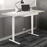 BDi Centro Sit+Stand Desk in Satin White on Oak with Grey Glass, 30 x 66 inch top, raised, beside a multi-function cabinet, in an office, 30" x 66" Top size
