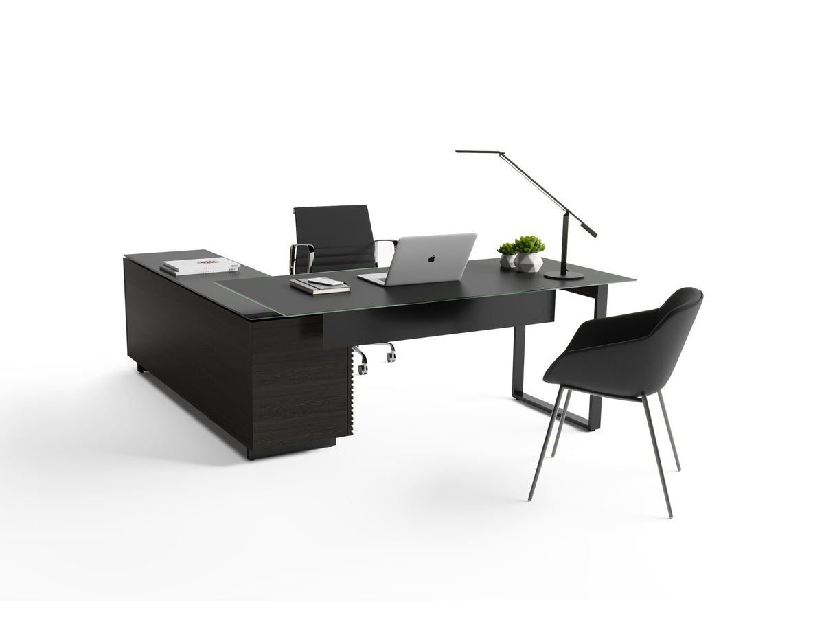 BDi Corridor 6531 L-Shaped Office Desk in Charcoal Stained Ash, back view with a desk chair and guest chair, on white