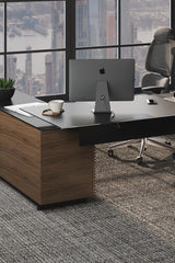 BDi Corridor 6531 L-Shaped Office Desk in Natural Walnut, back corner with a computer, in a high-rise office
