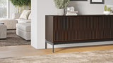 BDi Elements 8709 Media + Storage Console in Toasted Oak, beside a sofa in a living room, with Tune door fronts