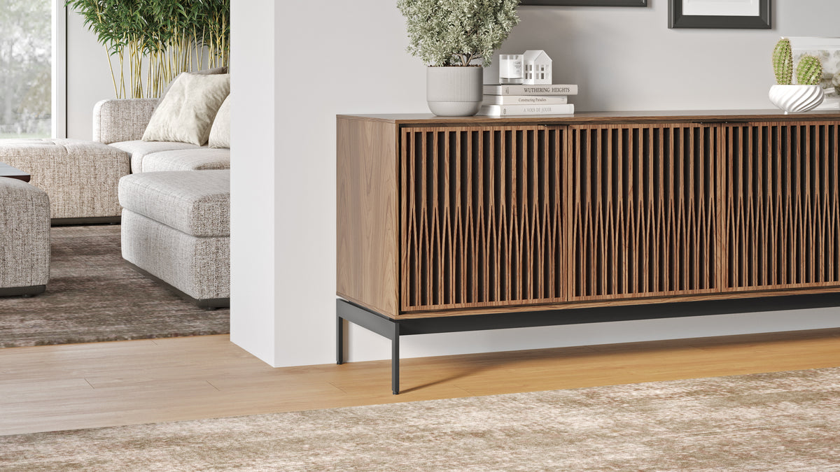 BDi Elements 8709 Media + Storage Console in Natural Walnut, beside a sofa in a living room, with Tune door fronts
