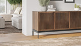 BDi Elements 8709 Media + Storage Console in Natural Walnut, beside a sofa in a living room, with Tune door fronts