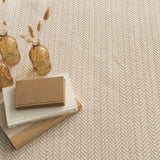 Dash & Albert Herringbone Handwoven Indoor/Outdoor Rug in Linen / White, close-up with books