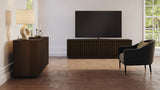 BDi Profile 8479 4-Door Media & Storage Console in Toasted Oak, with a TV in a living room, beside the 3-door cabinet