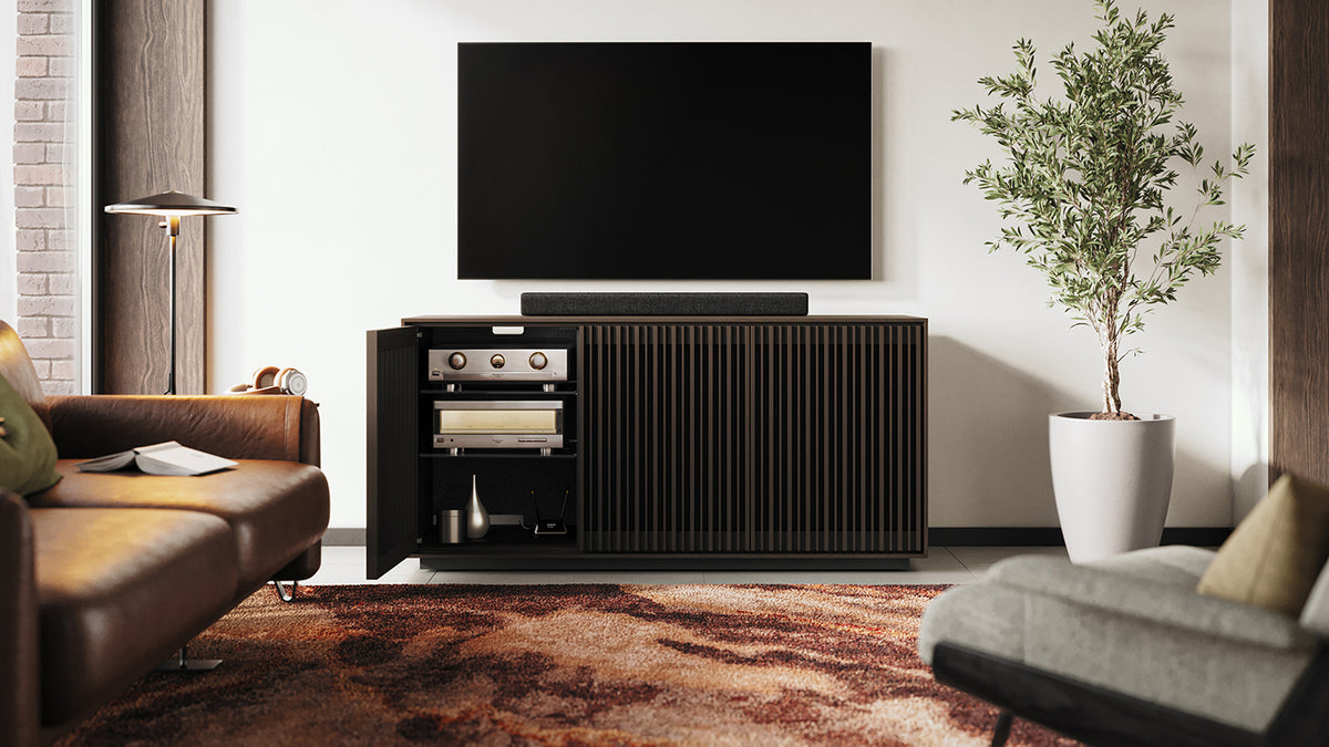 BDi Profile 8477 3-Door Media & Storage Console in Toasted Oak, left door open, in a living room with a TV