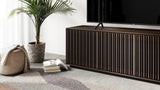 BDi Profile 8479 4-Door Media & Storage Console in Toasted Oak, angled close view with a TV, in a living room