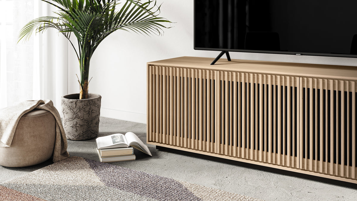 BDi Profile 8479 4-Door Media & Storage Console in Washed Oak, angled close view with a TV, in a living room