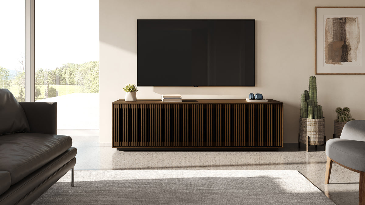 BDi Profile 8479 4-Door Media & Storage Console in Toasted Oak, in a living room under a wall-mounted TV