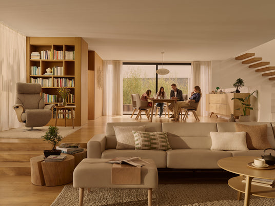 Family at a dining table behind a Stressless sofa and recliner in an open living room